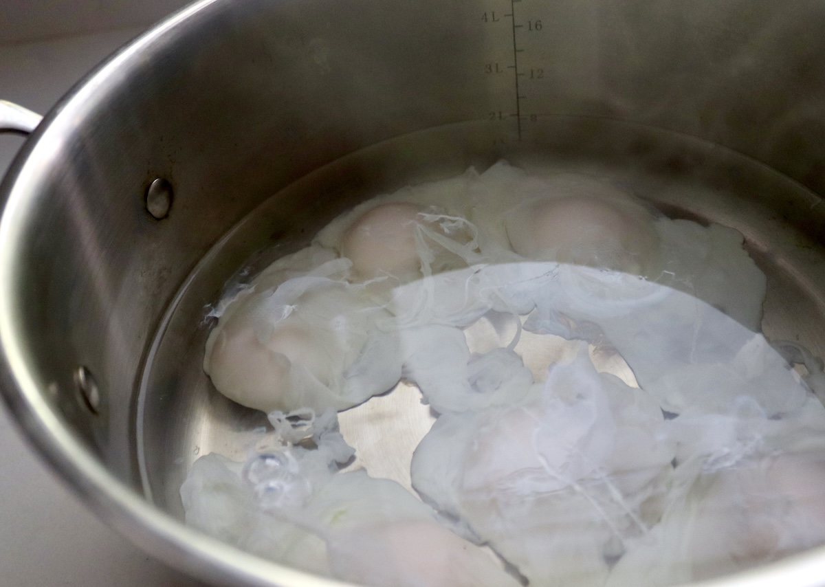 Eggs poaching in the bottom of a large pot.