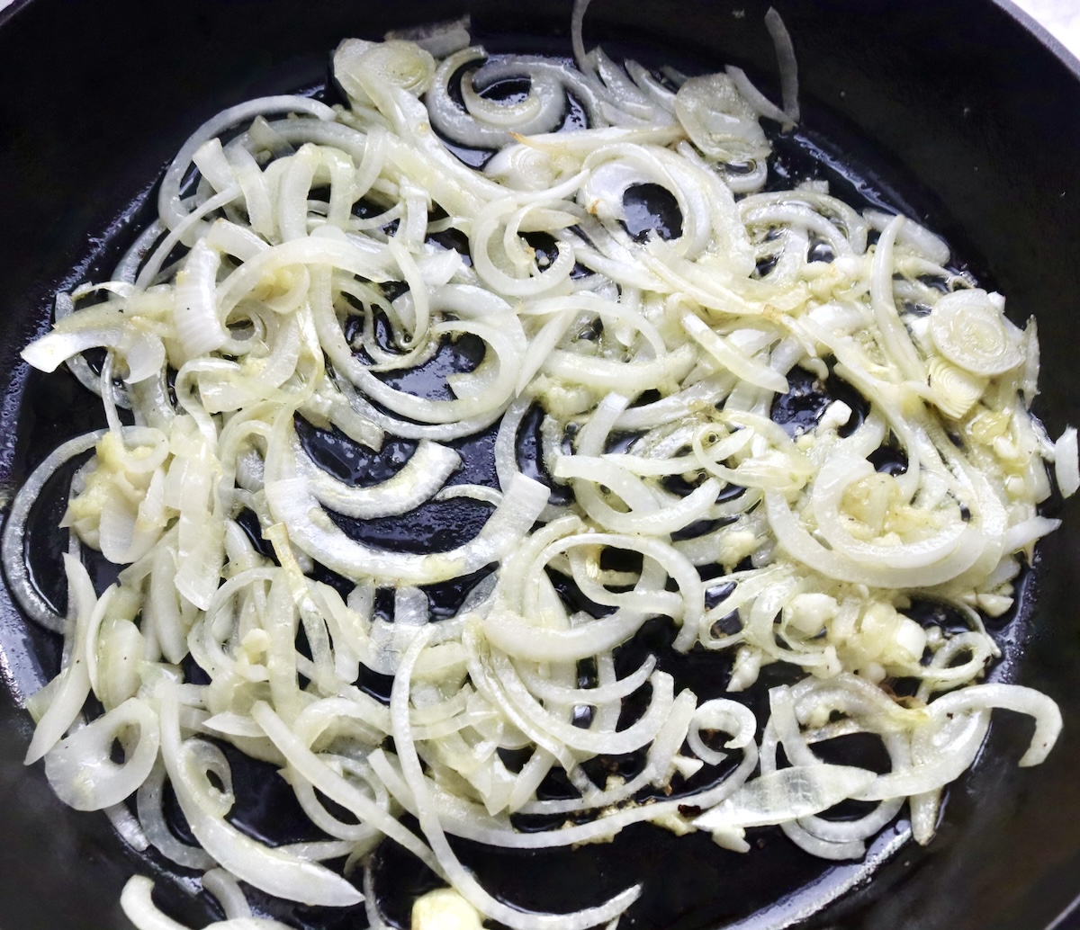 Raw sliced onion and garlic in a cast iron skillet.