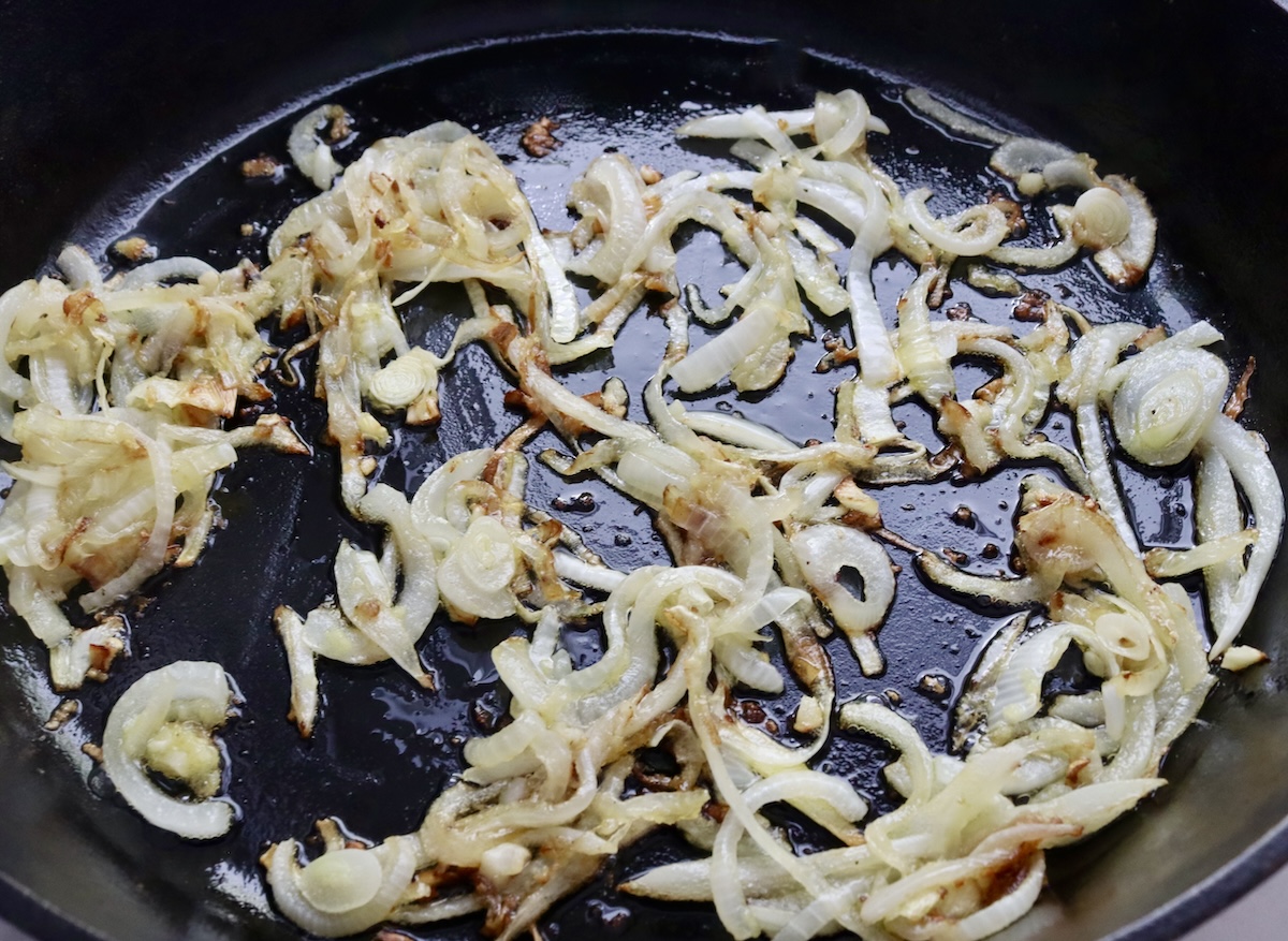 Sautéed sliced onion and minced garlic in a cast iron skillet.
