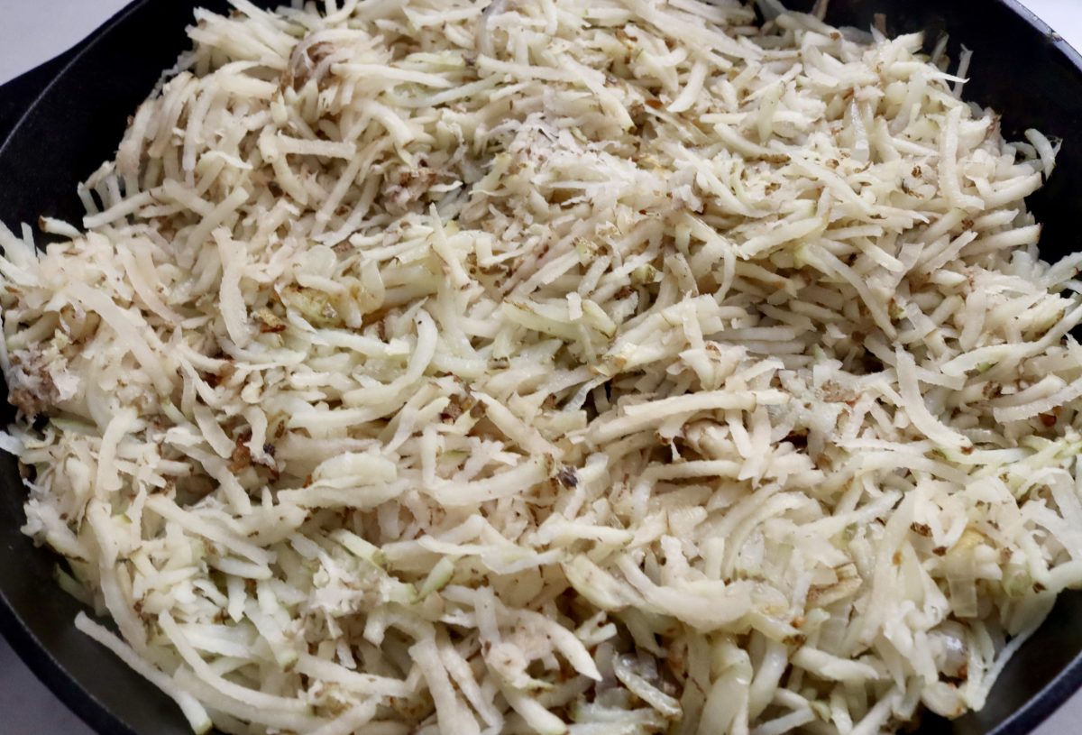 Grated Russet potatoes in a cast iron skillet.