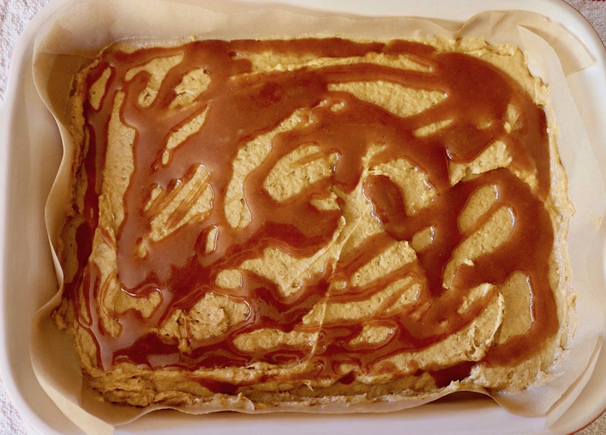 Baking dish with pumpkin coffee cake batter with drizzled caramel on top.
