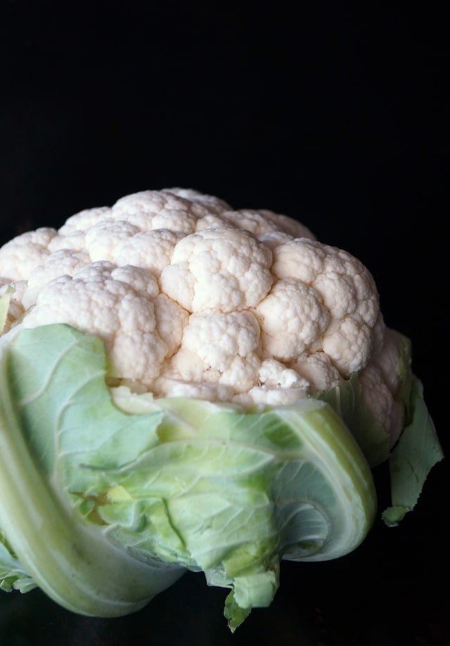 Roasted One large head of cauliflower with a black background.