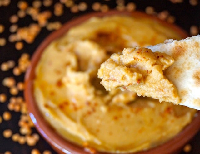 Smoky Red Lentil Hummus on a chip and in a teracotta bowl.