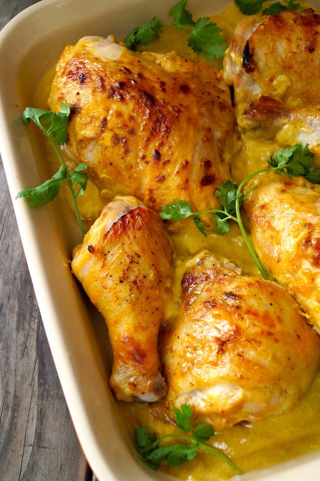 Baked Coconut Mango Chicken in cream colored baking dish with fresh cilantro