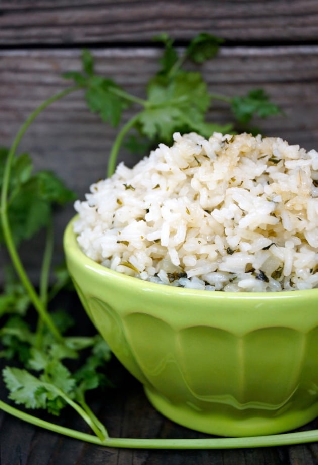 Coconut Cilantro Rice in a green bowl with cilantro sprigs in background