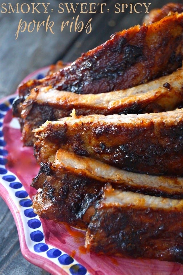 Smoky, Sweet and Spicy Pork Ribs piled on a dark magenta platter on a wood table