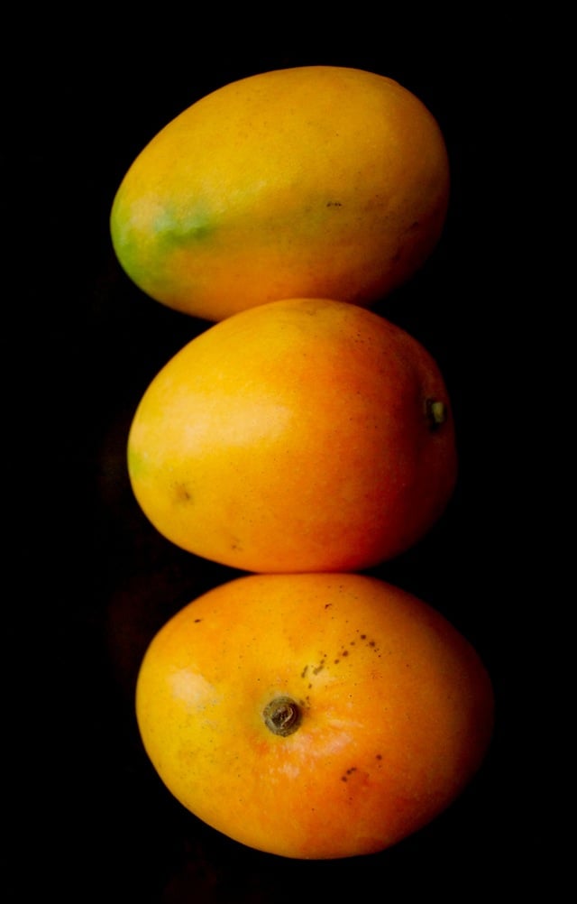 three stacked mangoes with black background