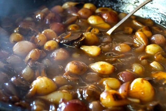 pearl onions in brown sauce in cast iron skillet