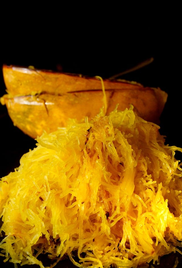 Pile of spaghetti squash with empty skins behind it