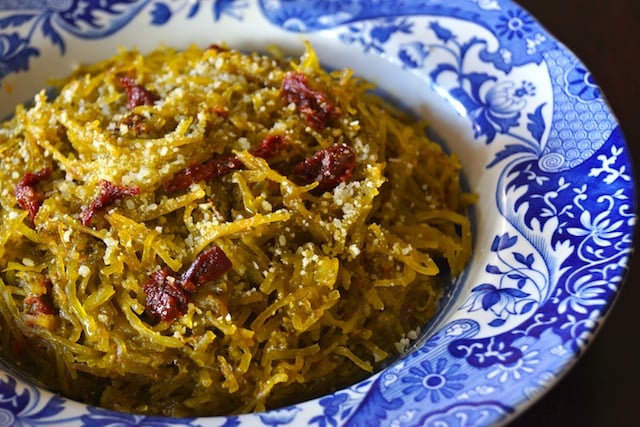 Pesto Spaghetti Squash Recipe in a pretty blue and white-rimmed bowl, with sun-dried tomatoes on top.