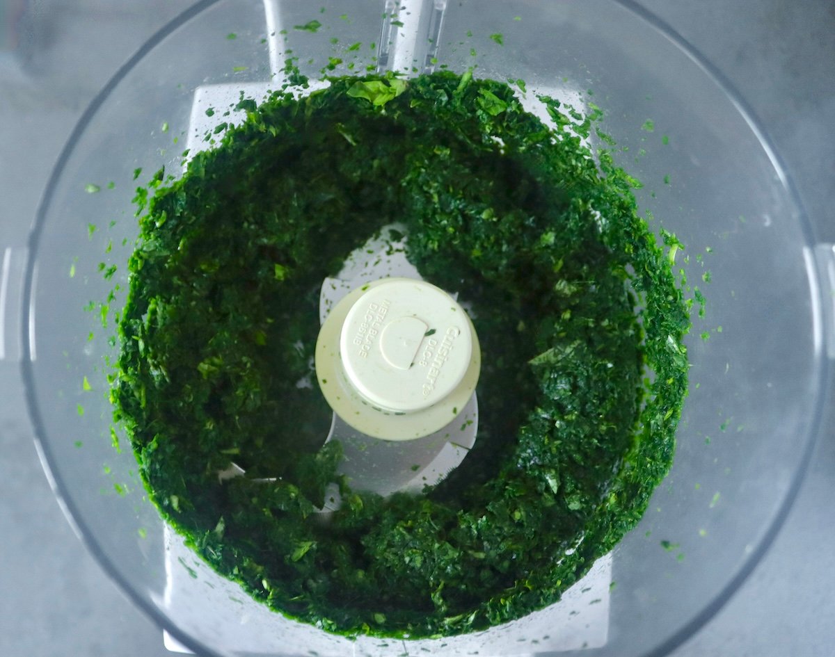 Finely chopped spinach and basil in a food processor bowl.