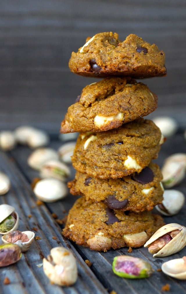 Tall stack of Gluten Free Pistachio Chocolate Chip-Cookies on wooden table surrounded by pistachios in their shells