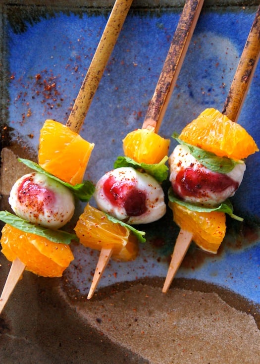 Three Citrus Mint Caprese Kebabs on a blue plate.