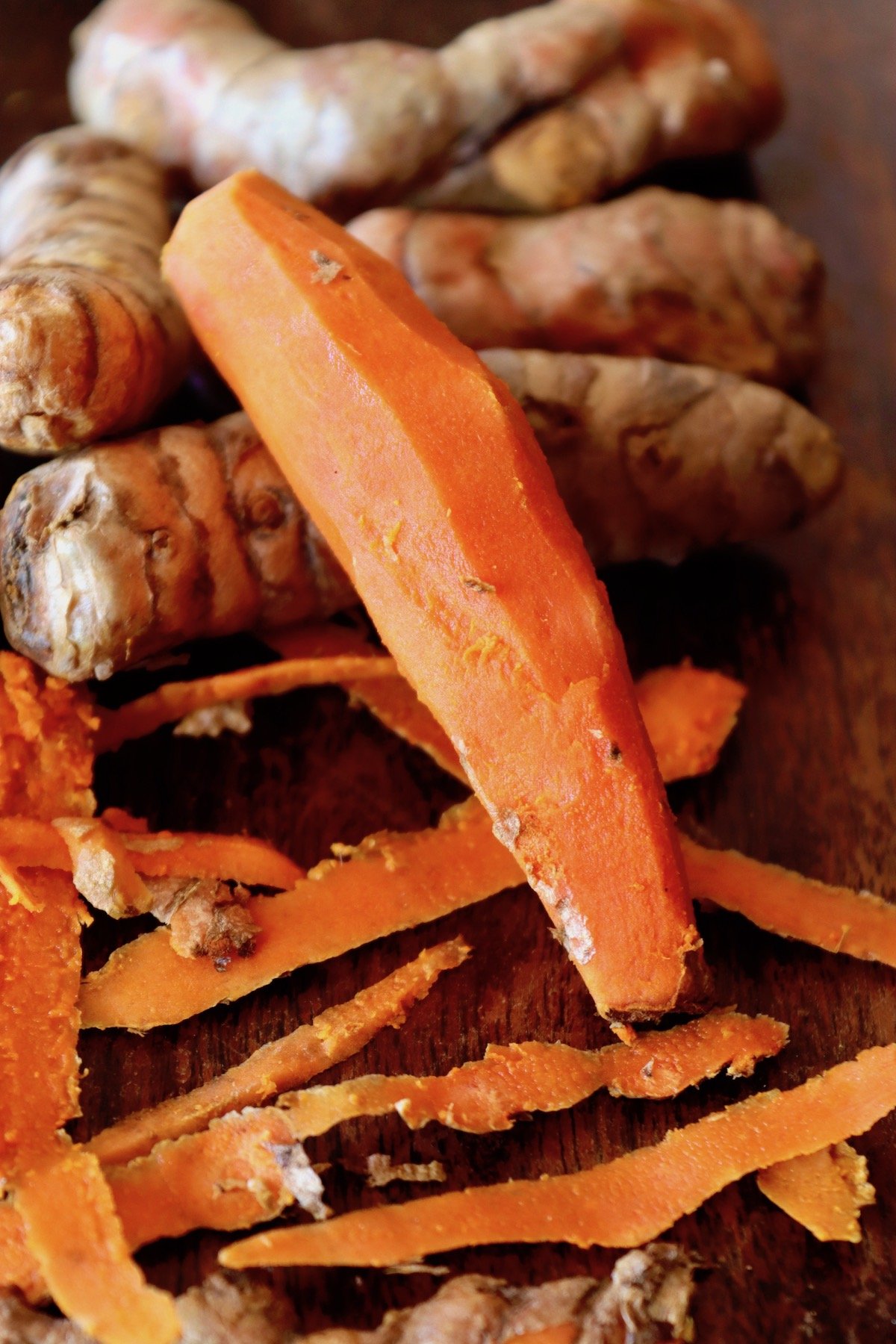 Peeled Turmeric root that looks like a carrot, with peels.
