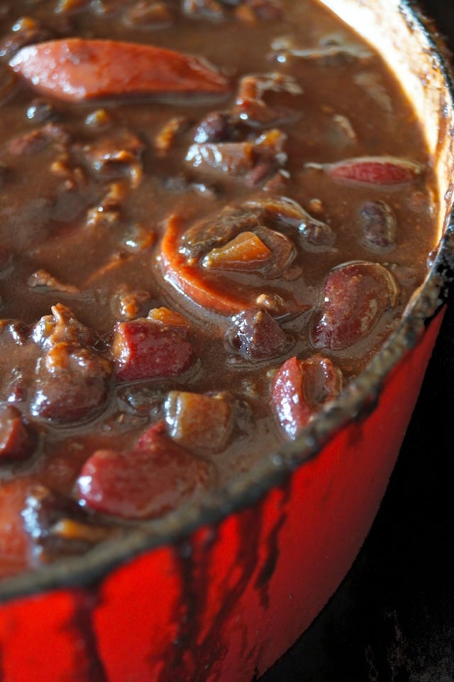 Knockwurst and the Best Baked Beans Ever in a red Dutch oven, spilling over the side a bit.