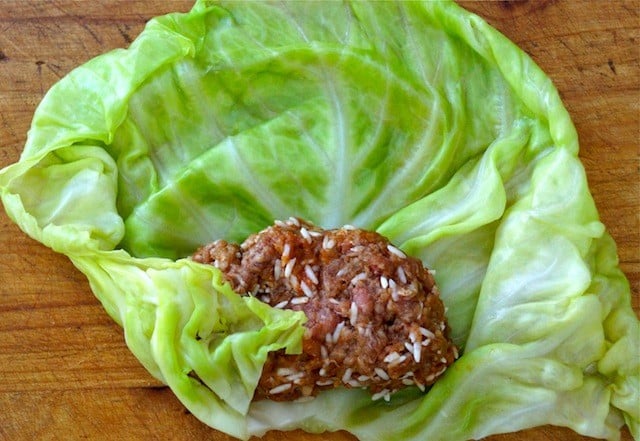 One beef and rice cabbage roll being wrapped on cutting board