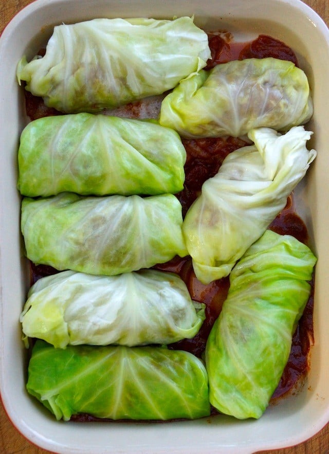 Stuffed Cabbage rolls on top of tomato sauce in baking pan