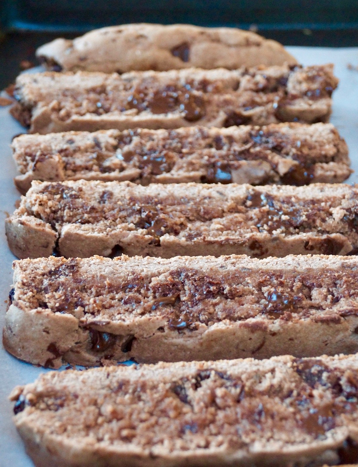 Slices of chocolate gluten-free biscotti on parchment paper