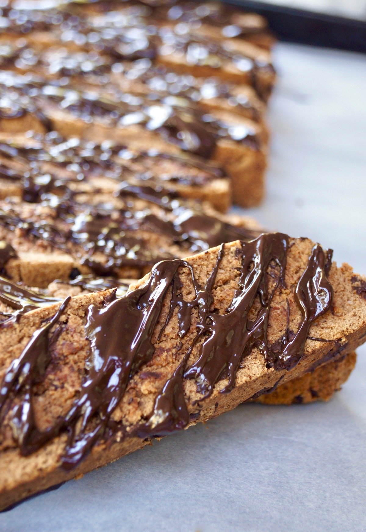 Gluten Free Chocolate Biscotti drizzled with melted chocolate on parchment paper 