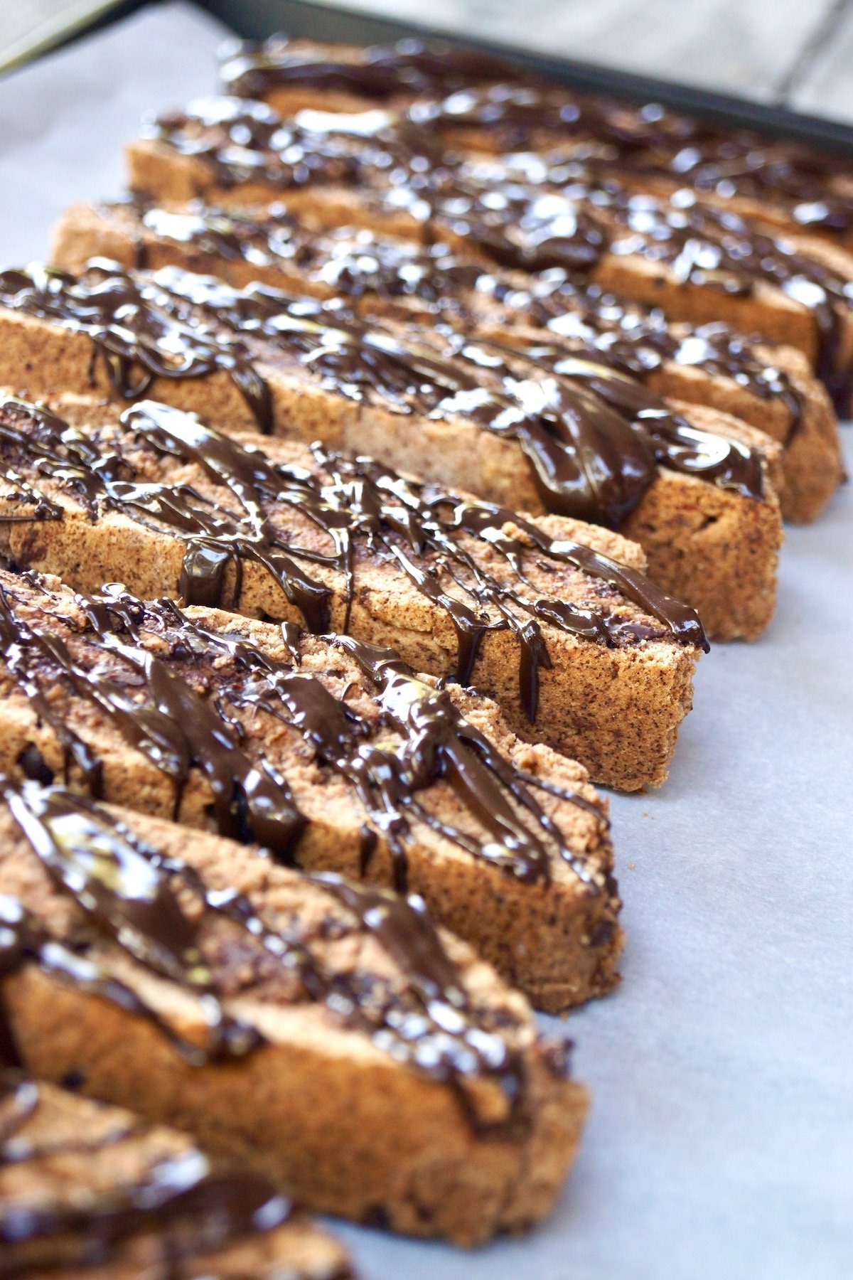 Gluten Free Chocolate Biscotti drizzled with melted chocolate on parchment paper 
