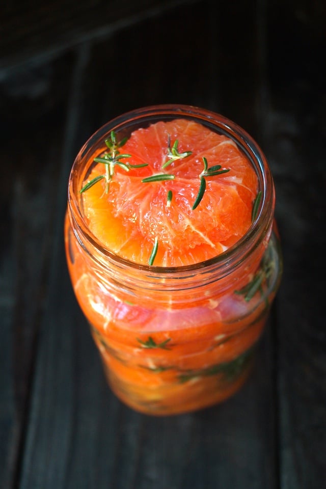 Mainated Oranges in a tall jar with fresh rosemary