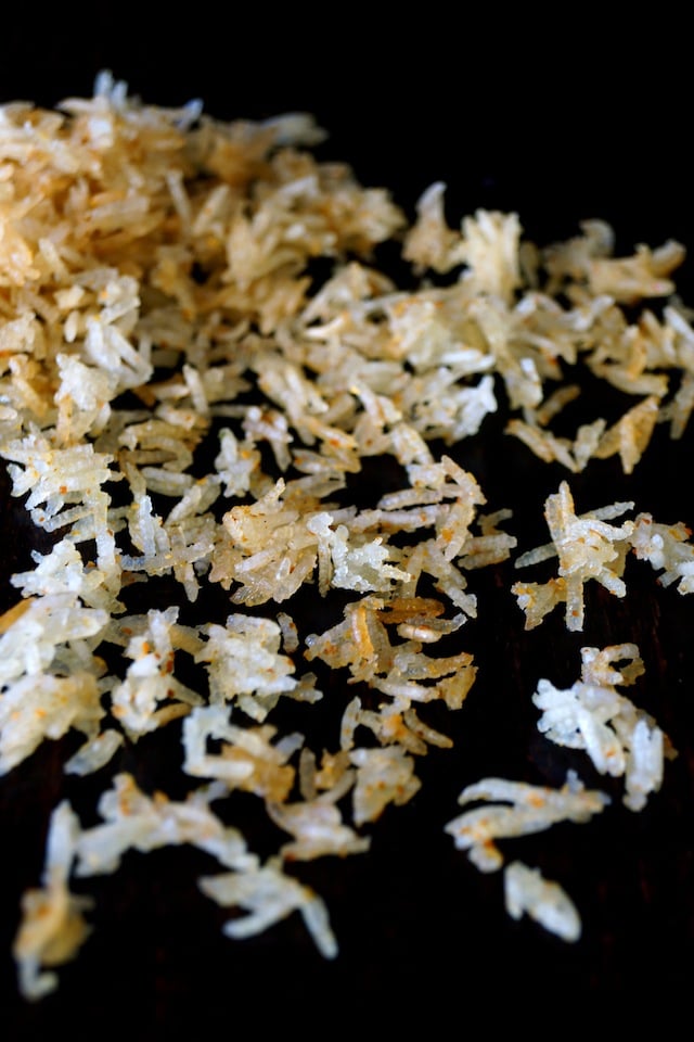 Spicy Crispy Rice strewn on a black surface.