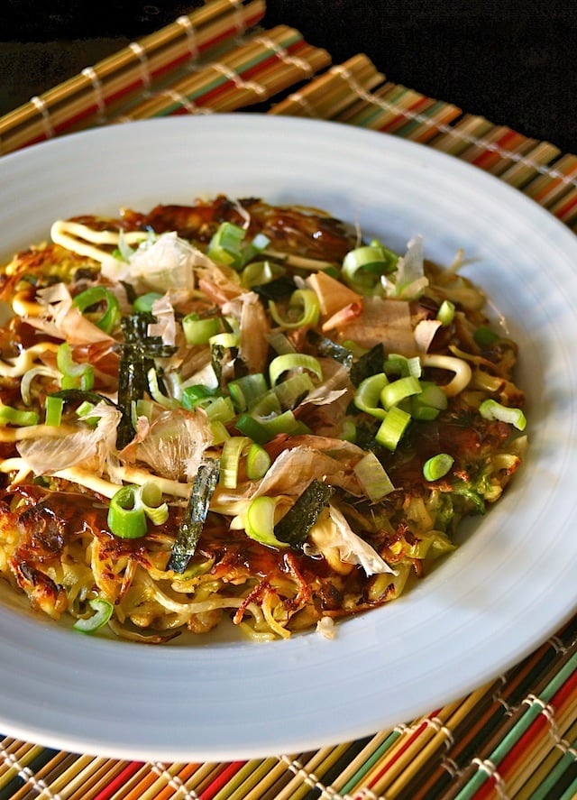 Yakisoba Okonomiyaki in white bowl on colorful bamboo mat