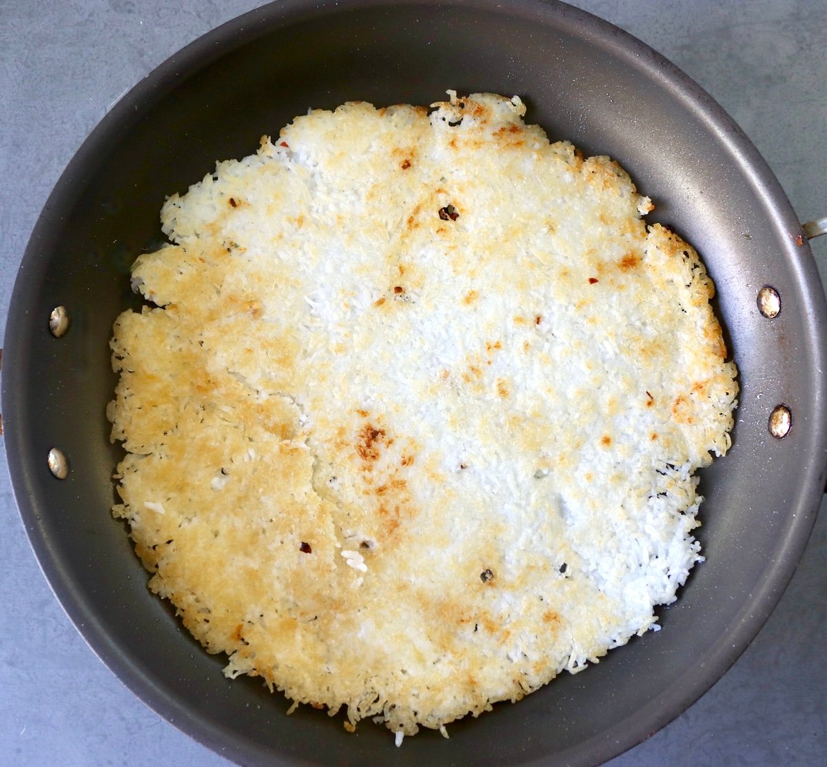 Golden crisped rice spread into the bottom of a large skillet.