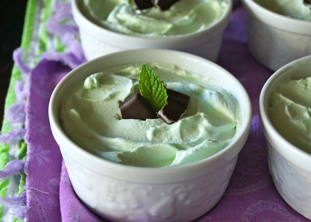 A few white ramekins with Grasshopper Mousse Pies on a purple cloth.