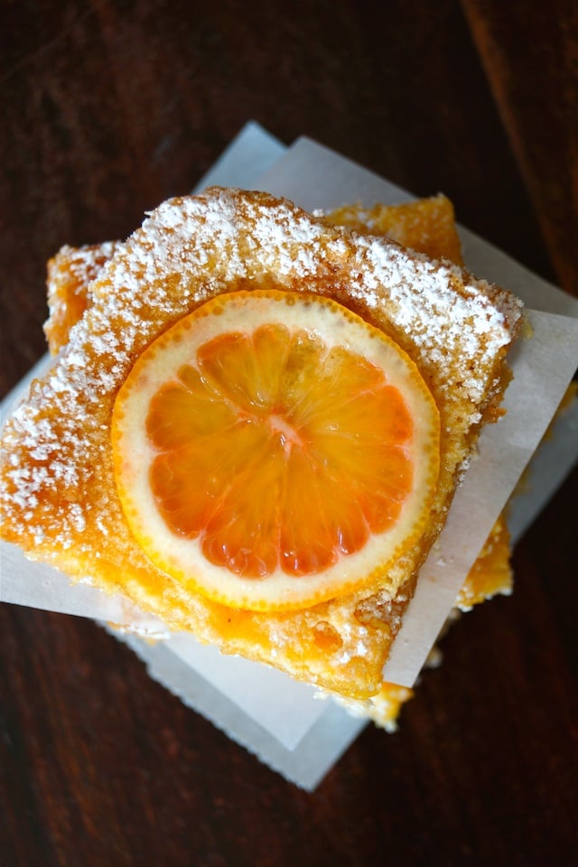 Top view of a stack of Gluten-Free Lemon Bars with Coconut Crust with parchment between each one.