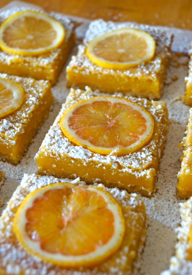 close up of a few Gluten-Free Lemon Bars with Coconut Crust on parchment.