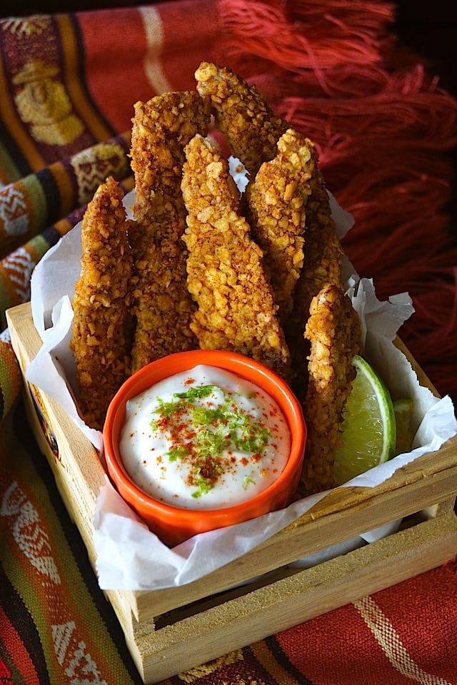 Tortilla Crusted Baked Chicken Strips Recipe and red bowl of Zesty Lime Crema in a small wooden box