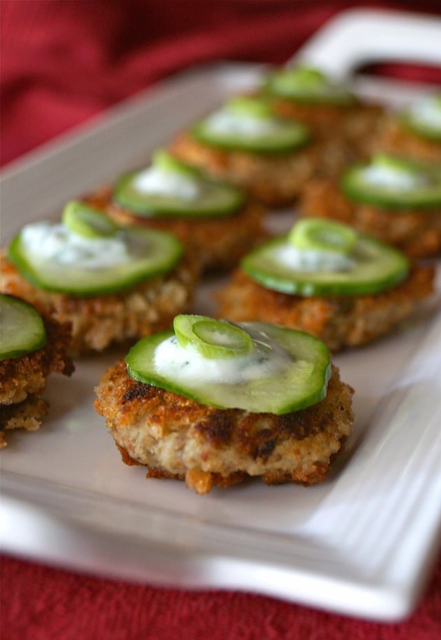 Eggplan Cakes with Lemon Sauce on a white platter with cucumber slices