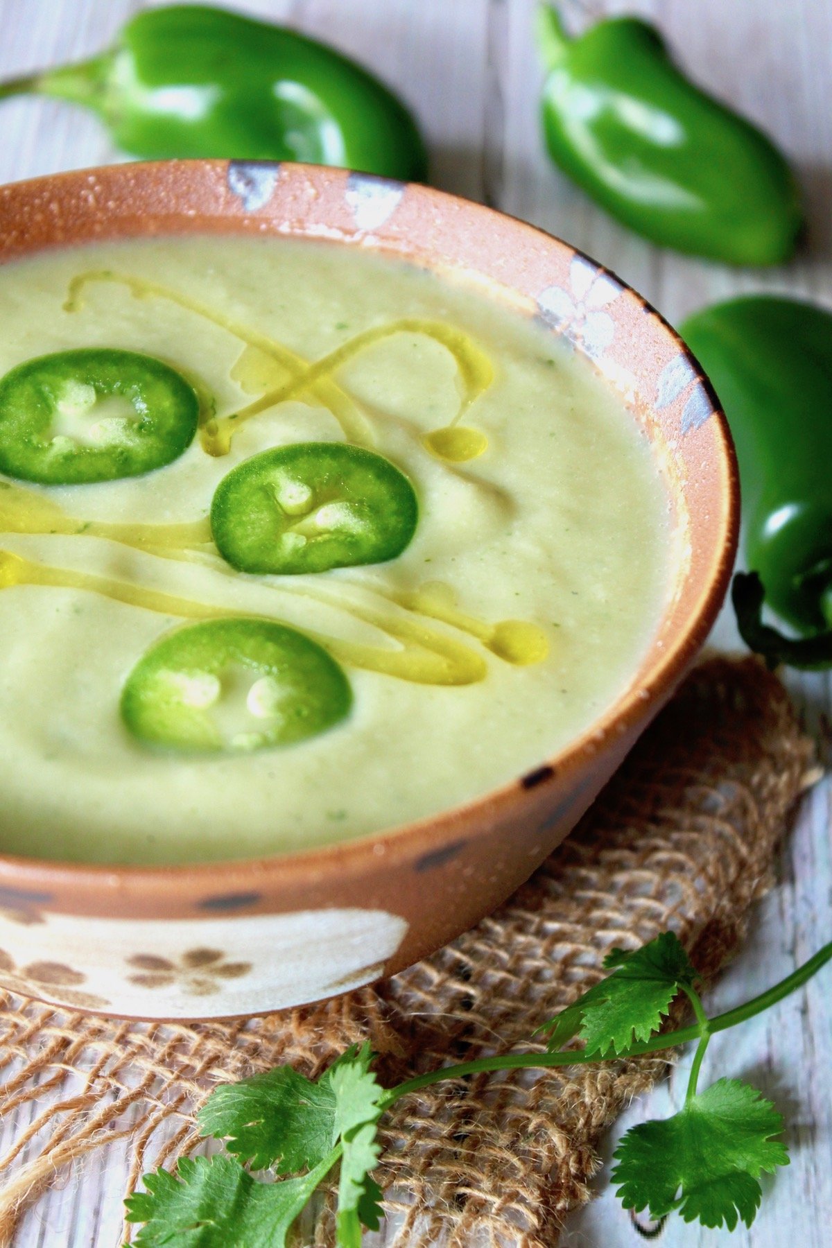 Cream of Jalapeno Cauliflower soup in rust-colored bowl with slices of jalapeno on top