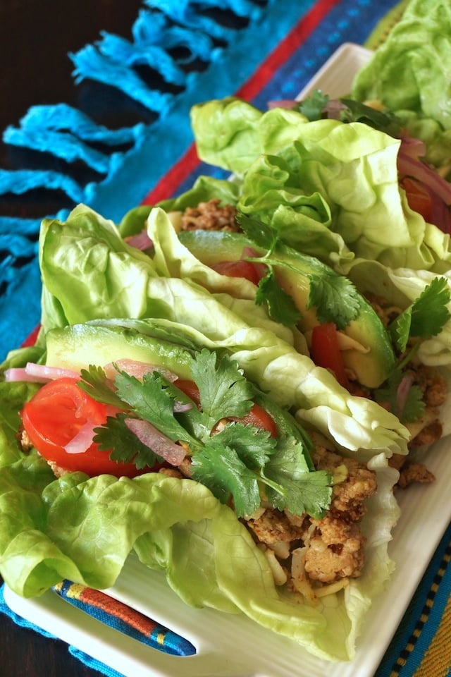 Pepper Jack Turkey Lettuce Tacos on a white plate on a bright turquoise cloth.