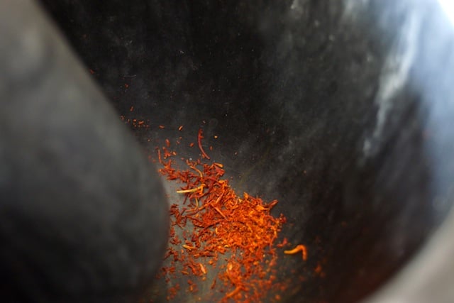 Saffron threads in dark grey mortar with a pestle.