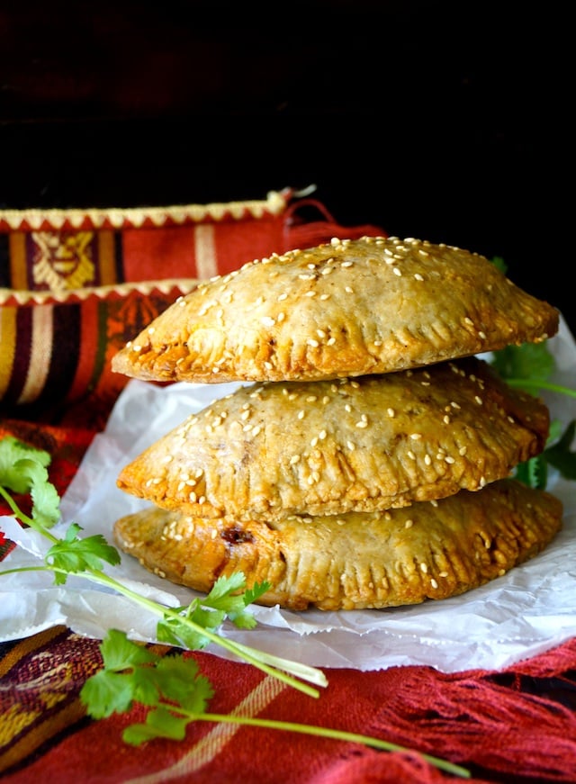 Stack of 3 Potato Chorizo Hand Pies on parchment paper with fresh cilantro.