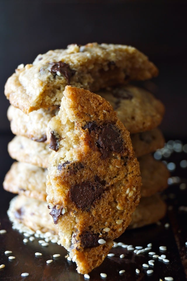 Close up of the bottom side of half of a Sesame Chocolate Chip Cookie Recipe, leaning agains a stack of them.