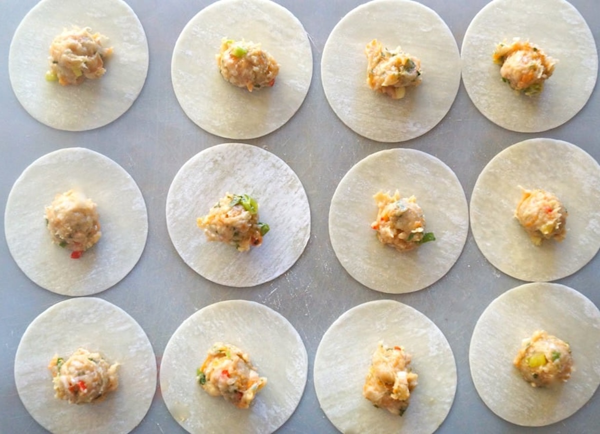 Ginger-Garlic-Chicken-Dumplings-Nepalese-Momo Garlic Ginger Chicken Dumplings being assembled on parchment paper with round wonton wrappers and ginger chicken filling.