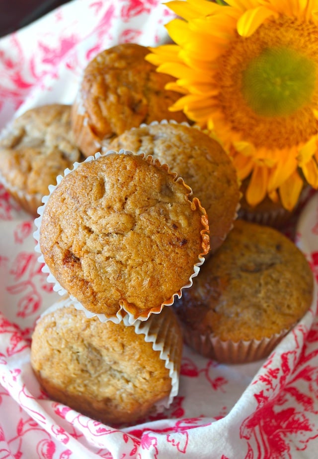 Honey Spiced Banana Muffins with a bright yellow sunflower with a pink and white cloth.