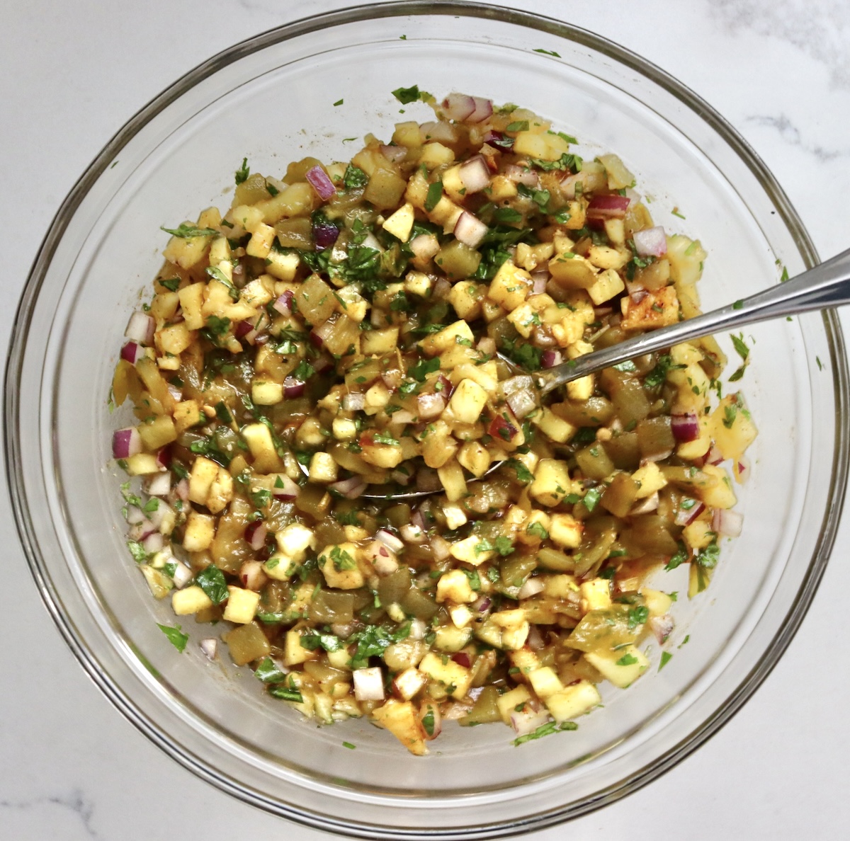 Pineapple-Salsa-Recipe Pineapple green chile salsa in a glass mixing bowl with a spoon.