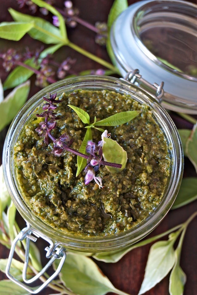 Top view of Lemon Verbena Pesto Recipe in a small jar with a purple basil flower on top.