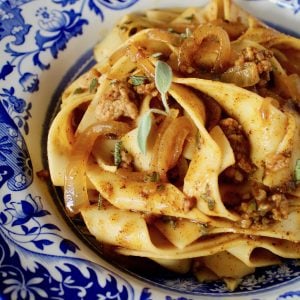 Pumpkin Pasta with Sausage mixed into Pappardelle in a blue and white bowl