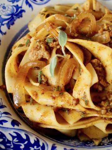 Pumpkin Pasta with Sausage mixed into Pappardelle in a blue and white bowl