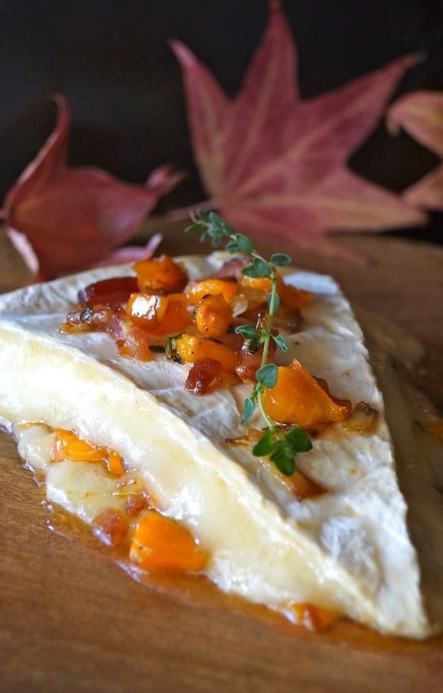 Cinnamon Persimmon Bacon Baked Brie Recipe melting on a cutting board