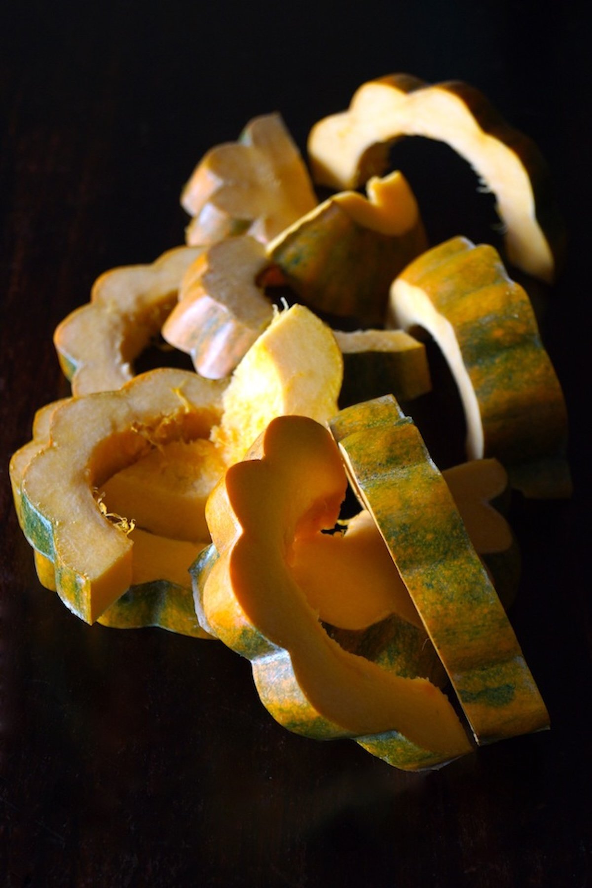 Several slices of an acorn squash on black background.