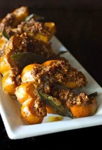 Roasted Pecan Crusted Acorn Squash with Crispy Sage Leaves on a white plate