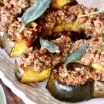White plate with several slices of baked acorn squash topped with a pecan crust.