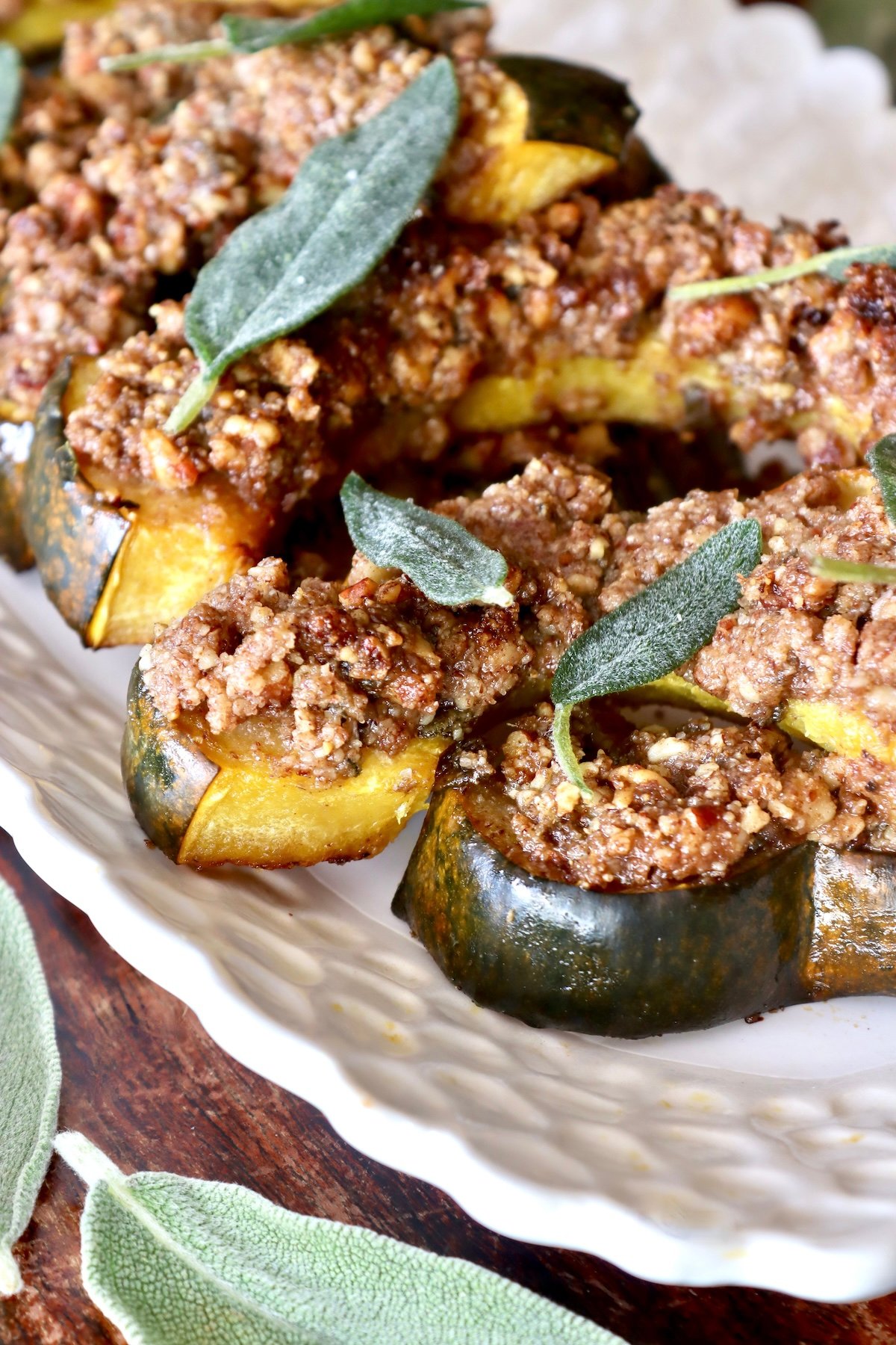 White plate with several slices of baked acorn squash topped with a pecan crust.