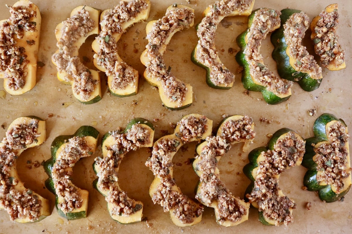 Several slices of pecan-crusted acorn squash on a parchment-lined baking sheet.